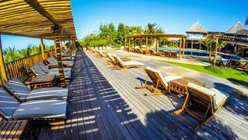 A wooden deck with sun loungers and a pool area.