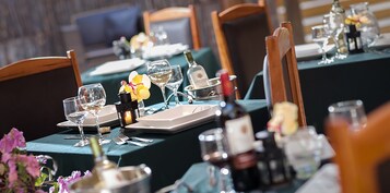 Una mesa de comedor dispuesta con platos, vasos y cubiertos, con una vela y flores sobre la mesa.