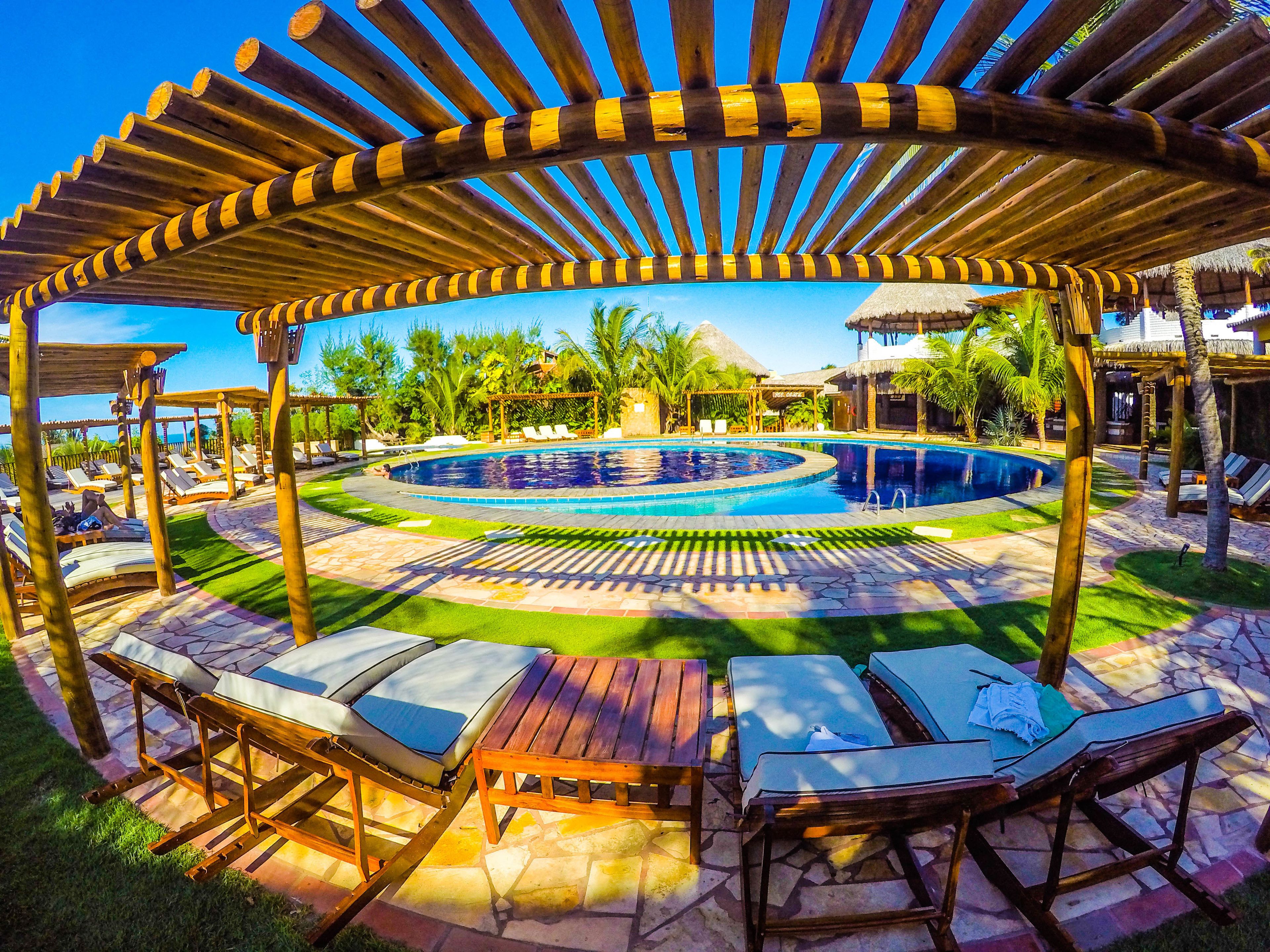 Un área de piscina con piscina circular, sillas de descanso y una pérgola de madera.