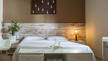 Una habitación de hotel con cama, mesita de noche, lámpara y una obra de arte colgada en la pared.