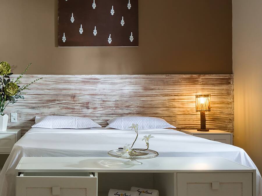 Una habitación de hotel con cama, mesita de noche, lámpara y una obra de arte colgada en la pared.