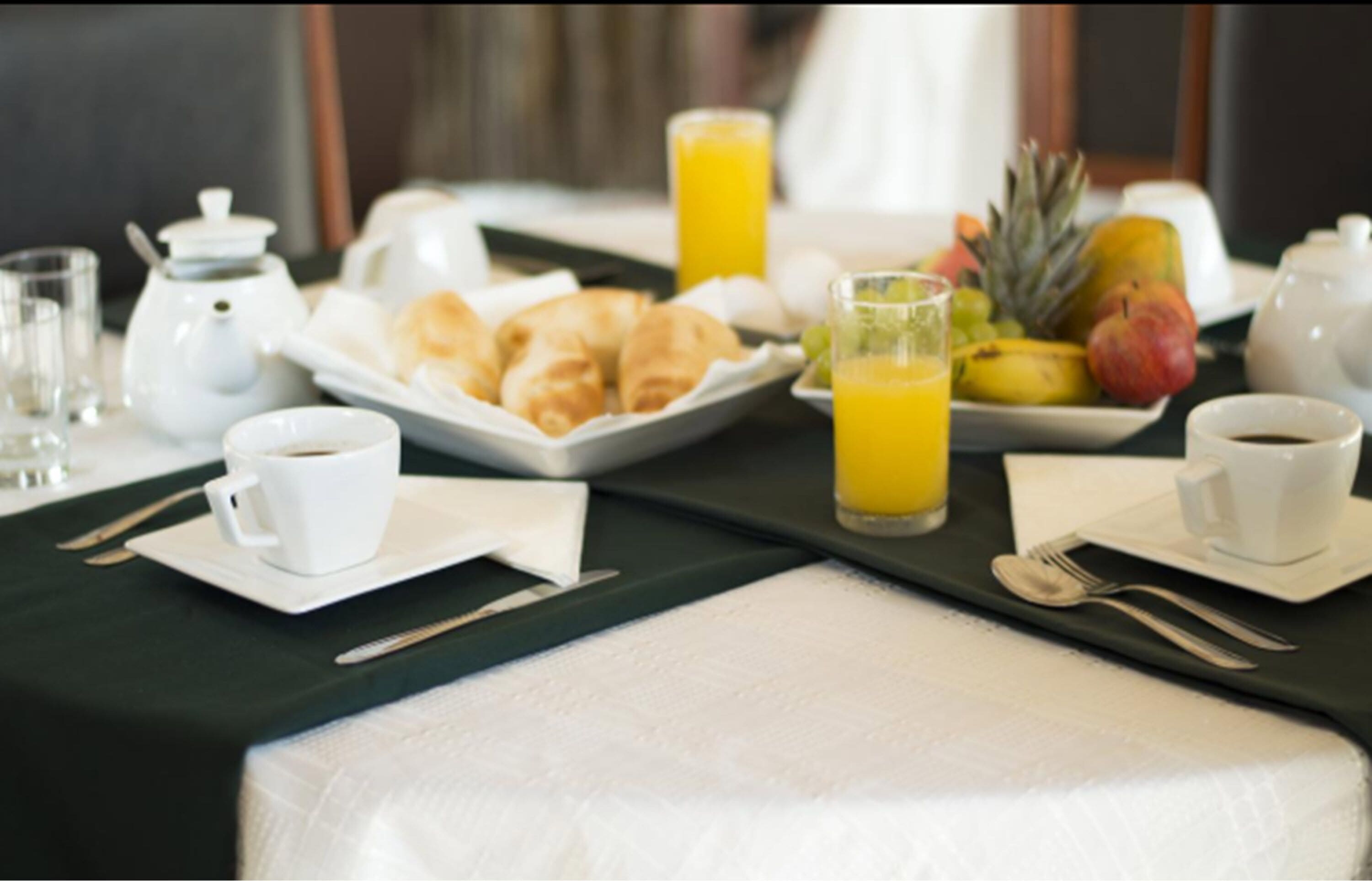 Een ontbijt opstelling met croissants, fruit en drankjes op een tafel.