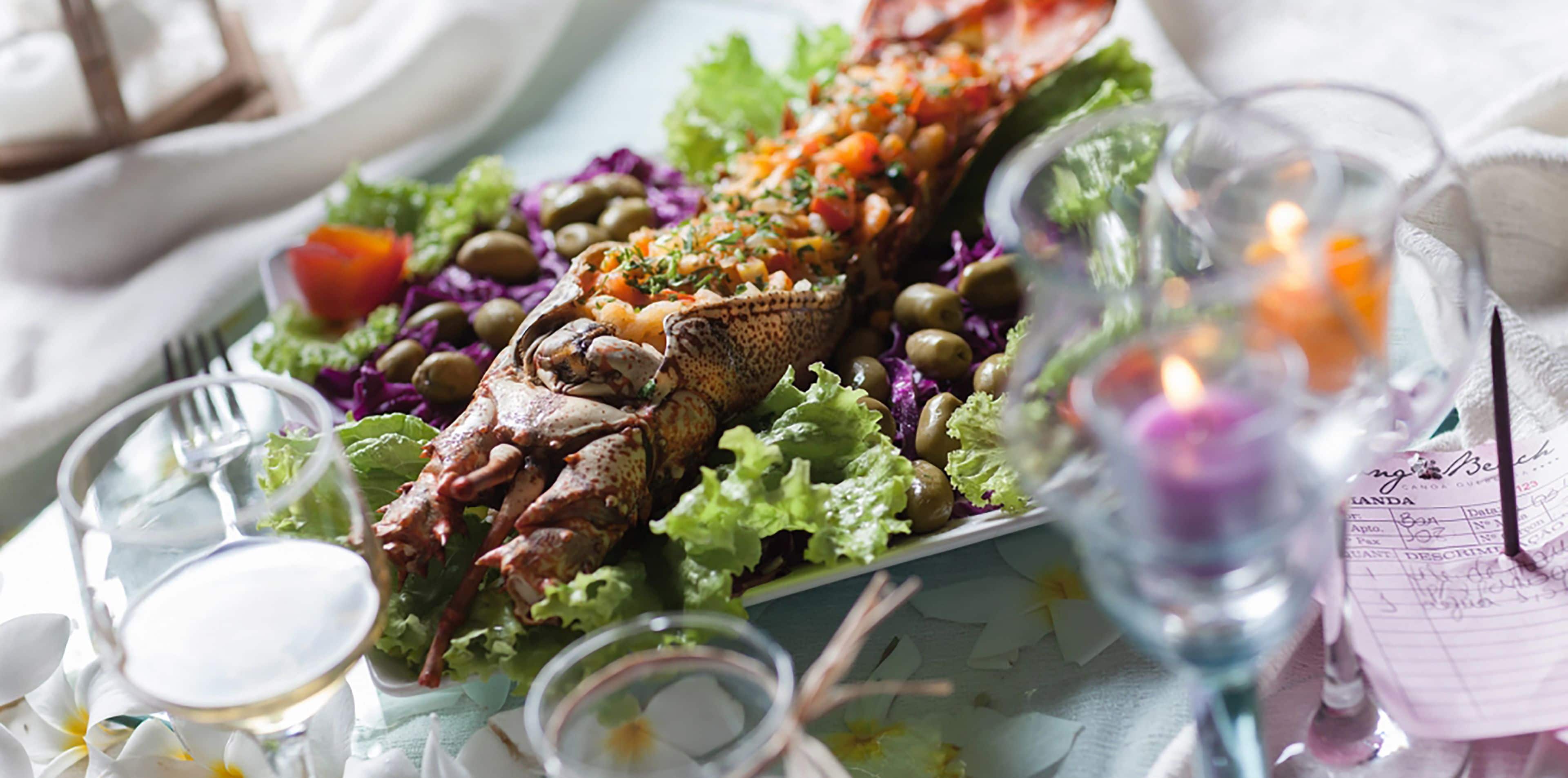 Un plateau de fruits de mer comprenant un poisson entier, des olives et des légumes, présenté sur une table.