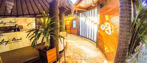 A reception area with a wooden reception desk, a thatched roof, and a mosaic floor.