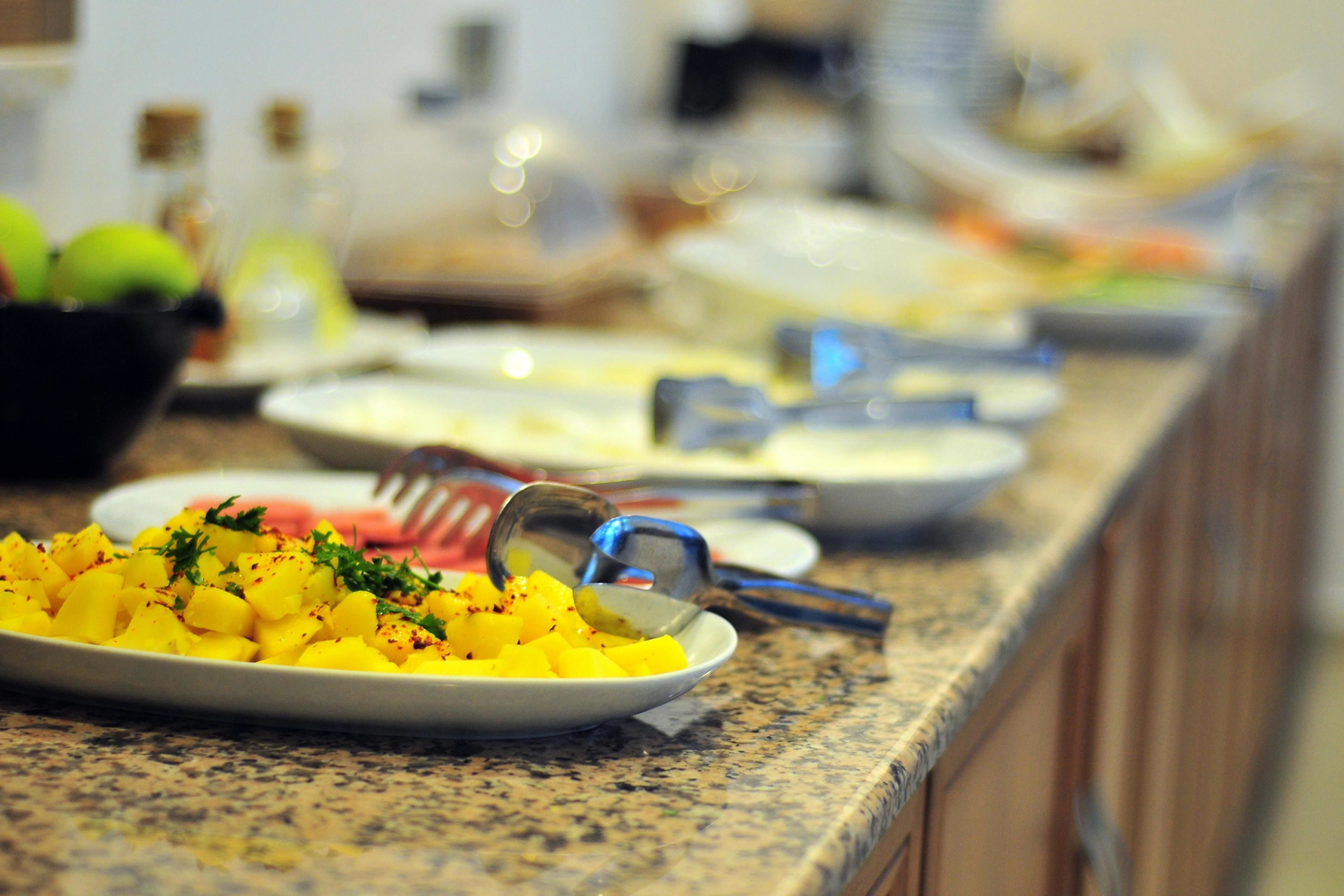 A buffet setup with various dishes, including a plate of diced yellow fruit garnished with herbs.
