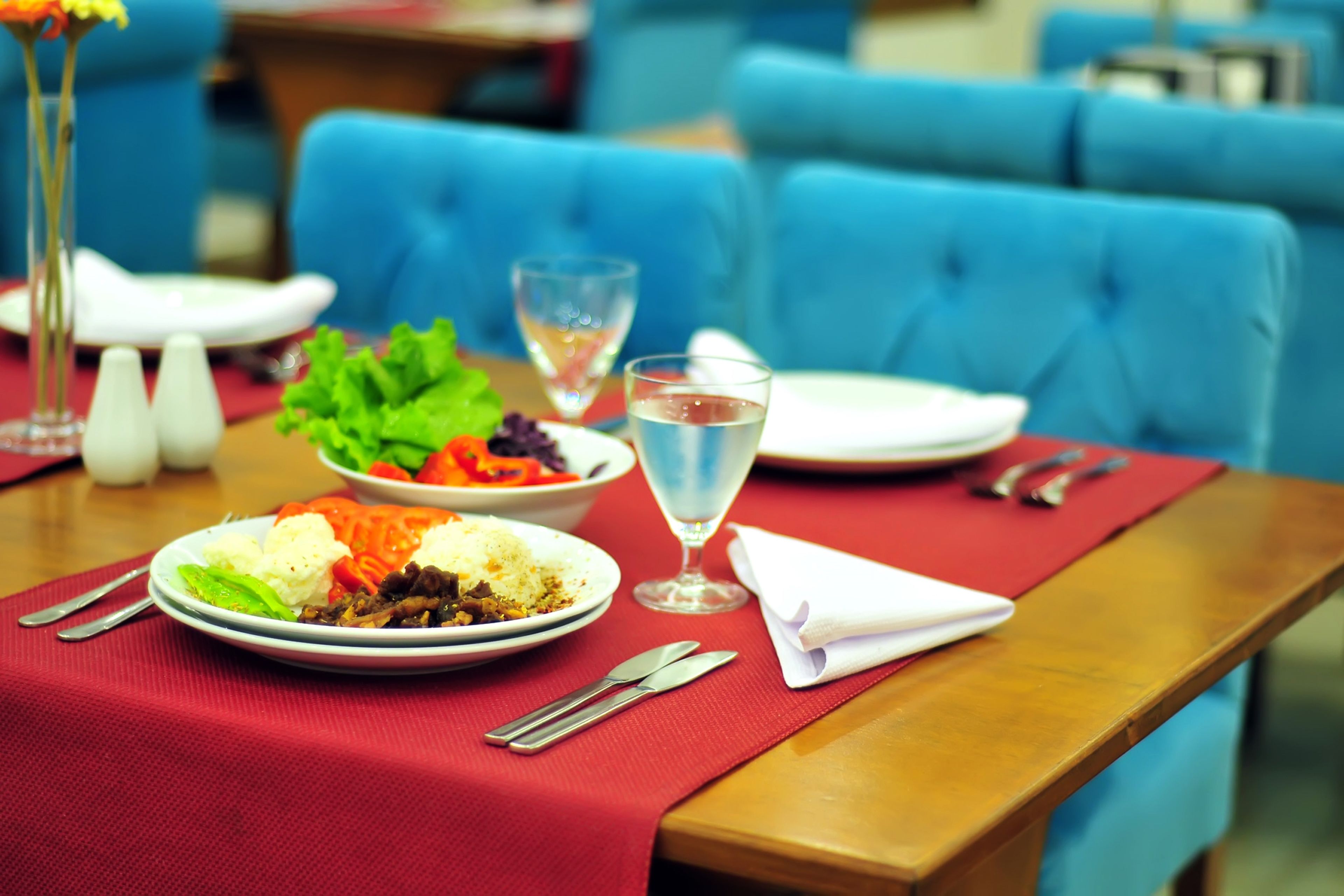 A dining table with plates of food, cutlery, and a glass of water.