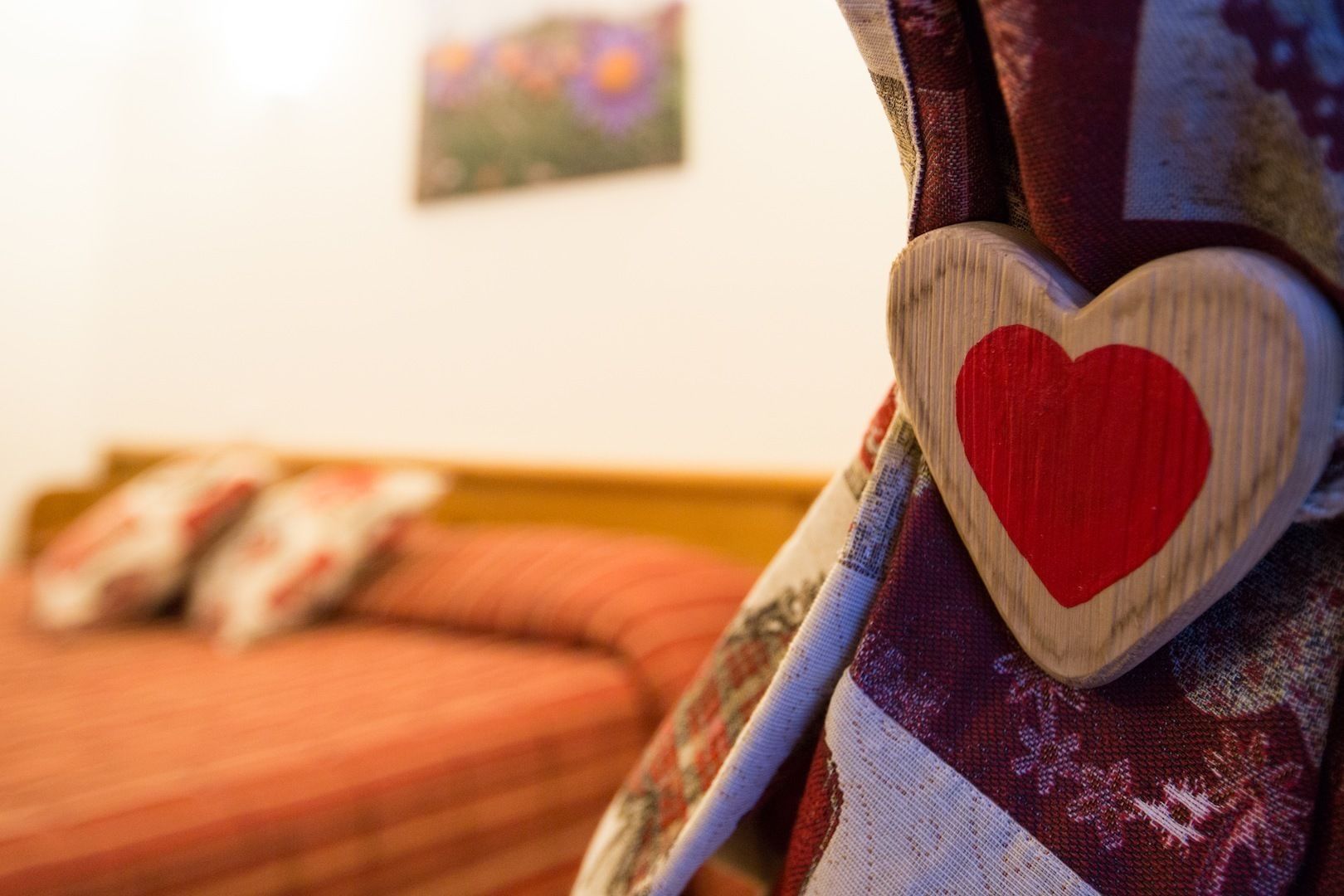 Primer plano de una almohada con forma de corazón de madera sobre una cama con tela estampada.