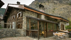 A rustic stone building with a wooden facade, large windows, and a sign indicating it is a hotel. - La Barme (Cogne)
