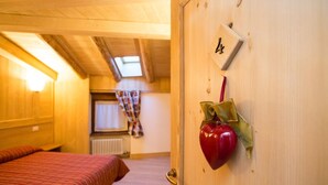 A wooden room with a bed, a radiator, and a window with curtains. - La Barme (Cogne)