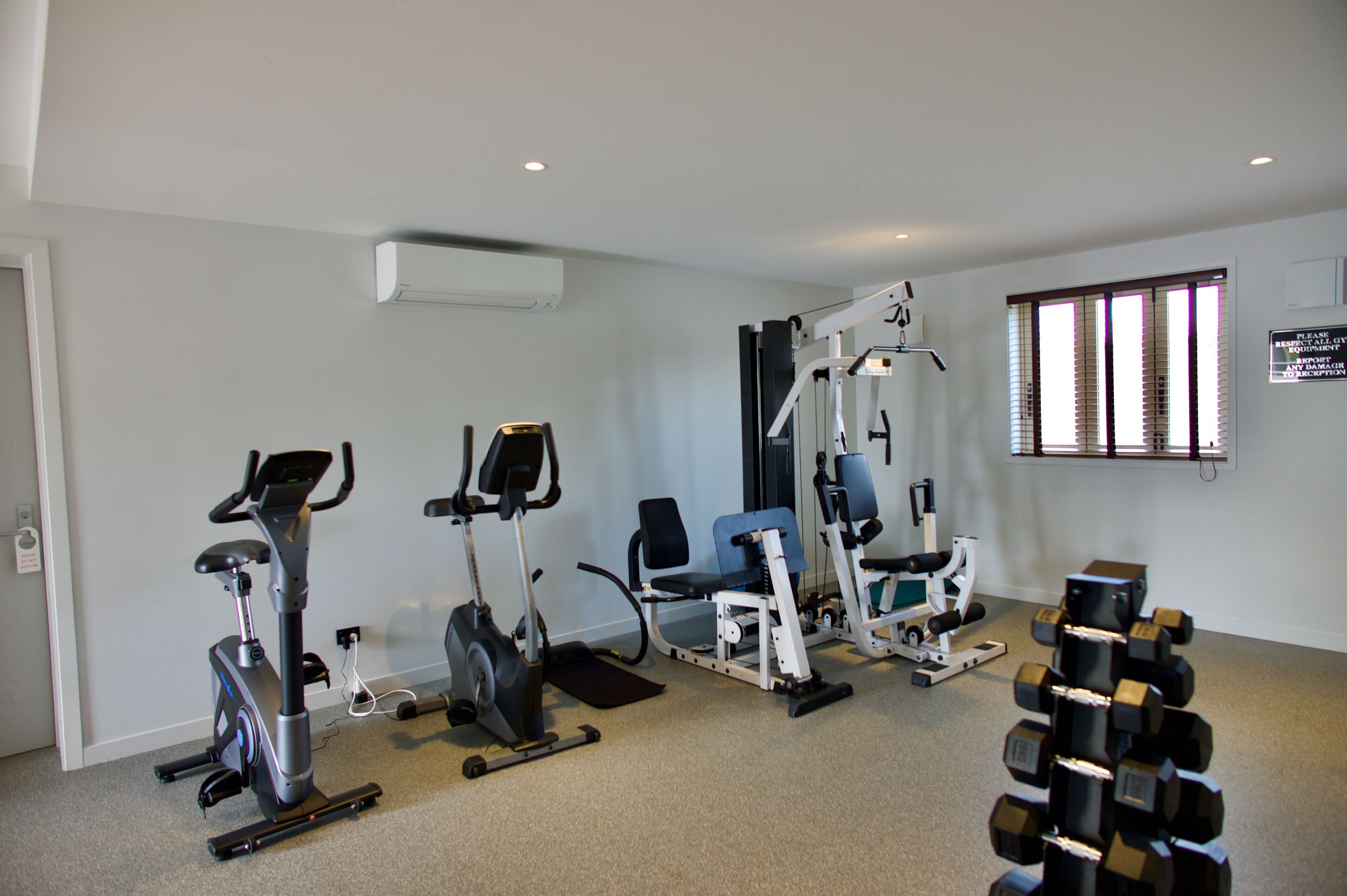A gym with stationary bikes, a rowing machine, and a set of dumbbells.