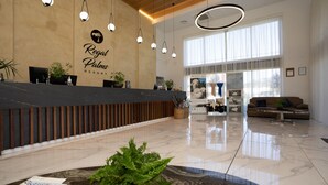 A spacious lobby with a reception desk, modern lighting, and a large window providing natural light. - Regal Palms Resort (Rotorua)