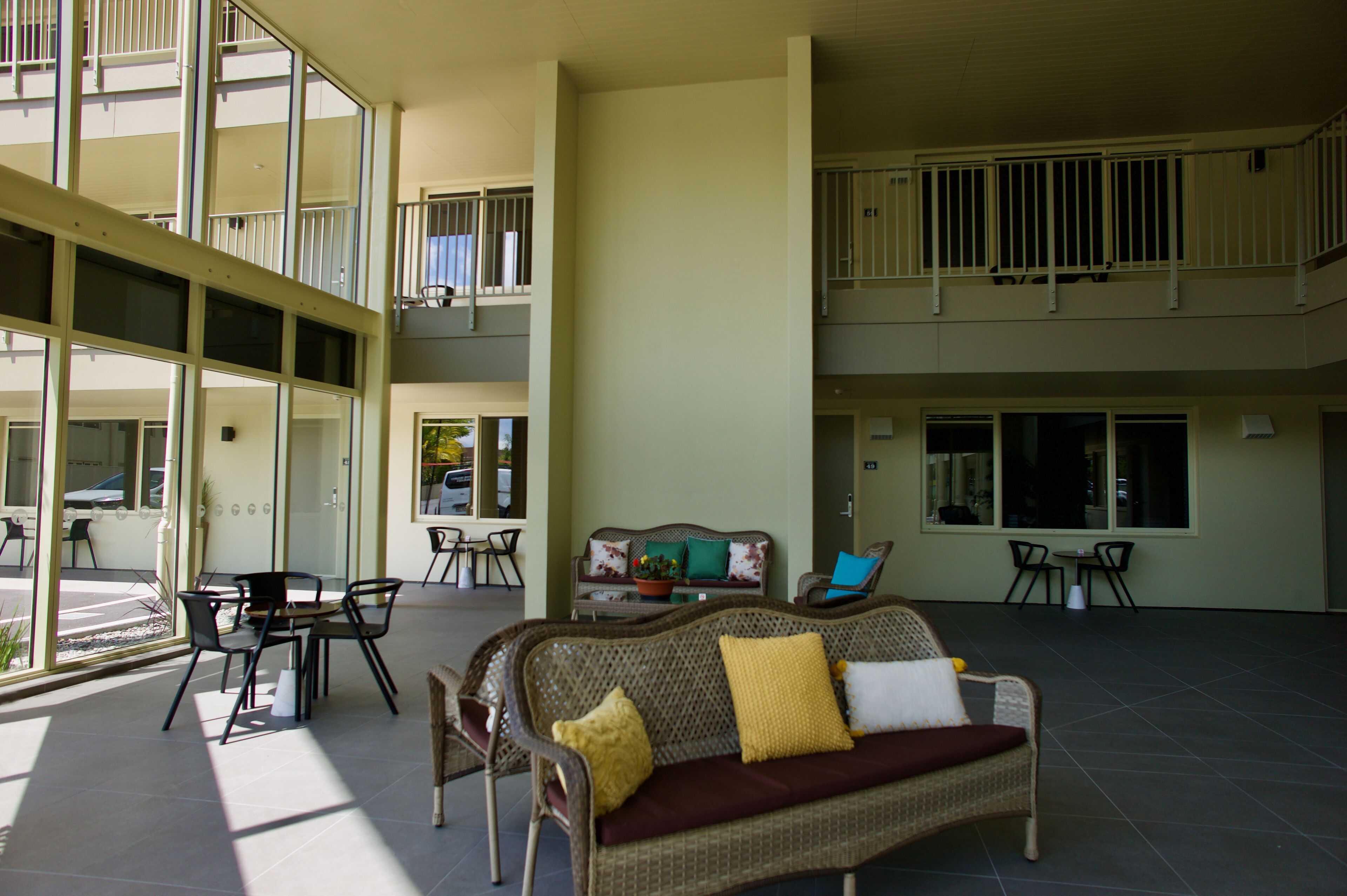 A spacious indoor area with a wicker sofa, chairs, and a dining table.