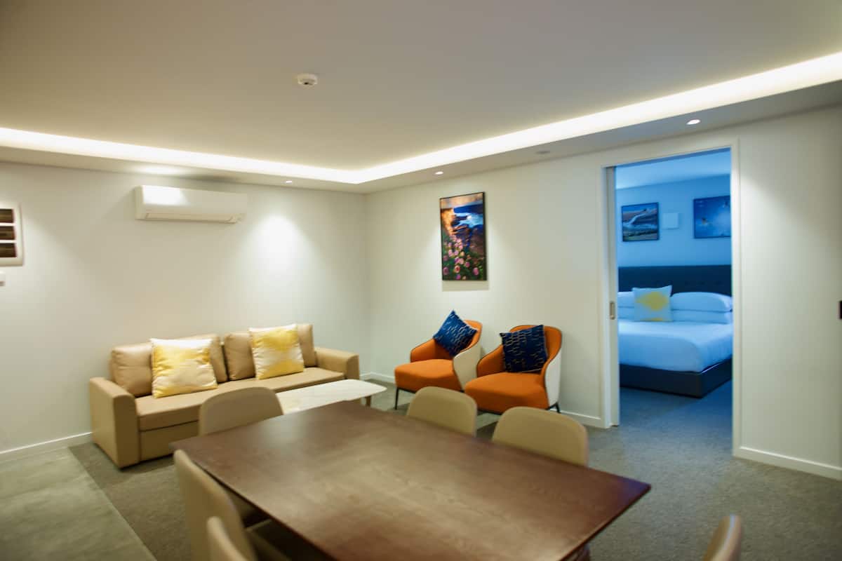 Une chambre d’hôtel moderne équipée d’un canapé, de fauteuils, d’une table à manger et d’un lit.