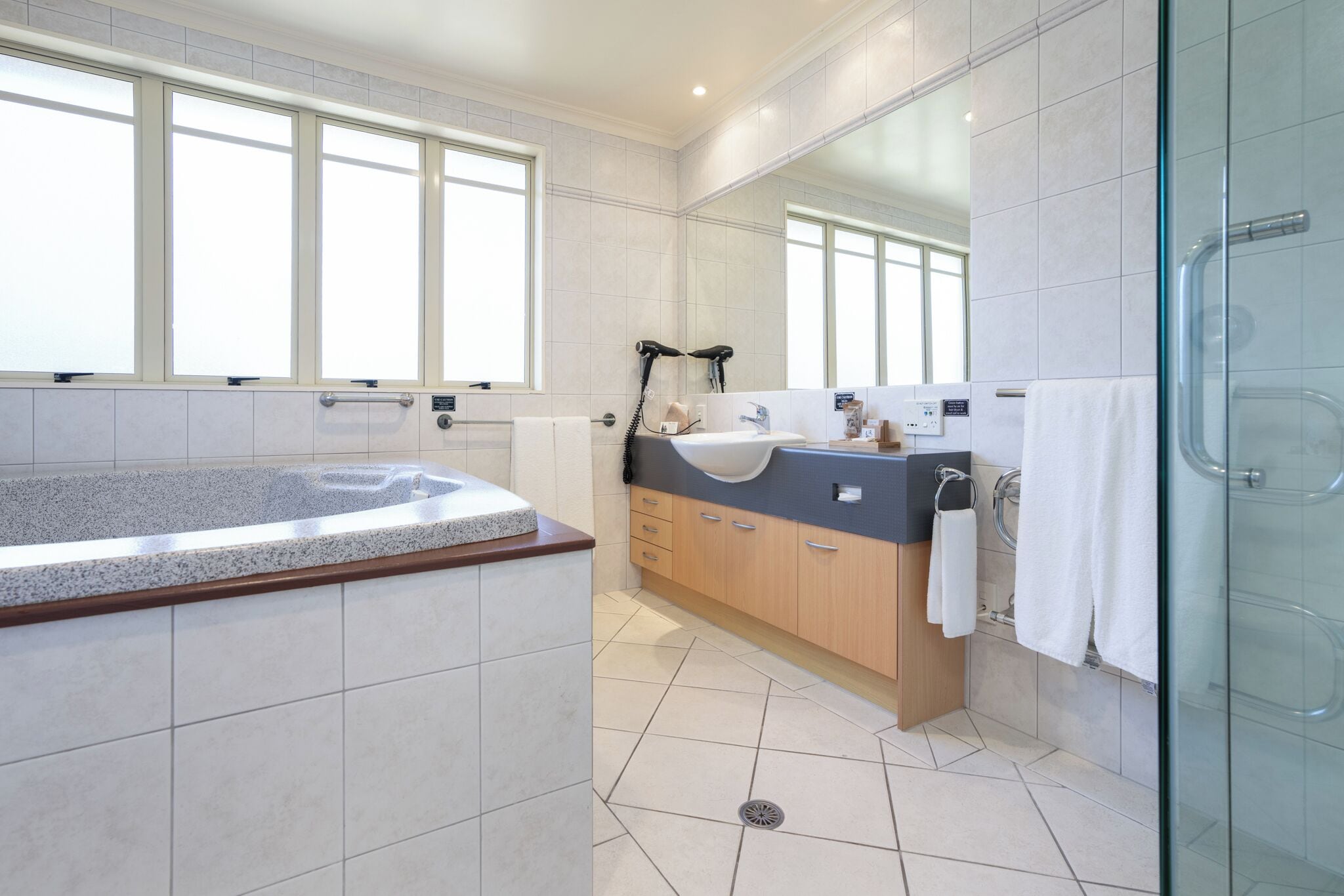 A modern bathroom with a large bathtub, a vanity with a sink, and a glass shower enclosure.