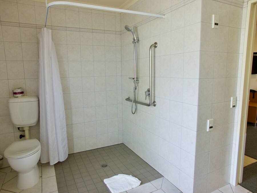 A bathroom with a shower, toilet, and a towel on the floor.