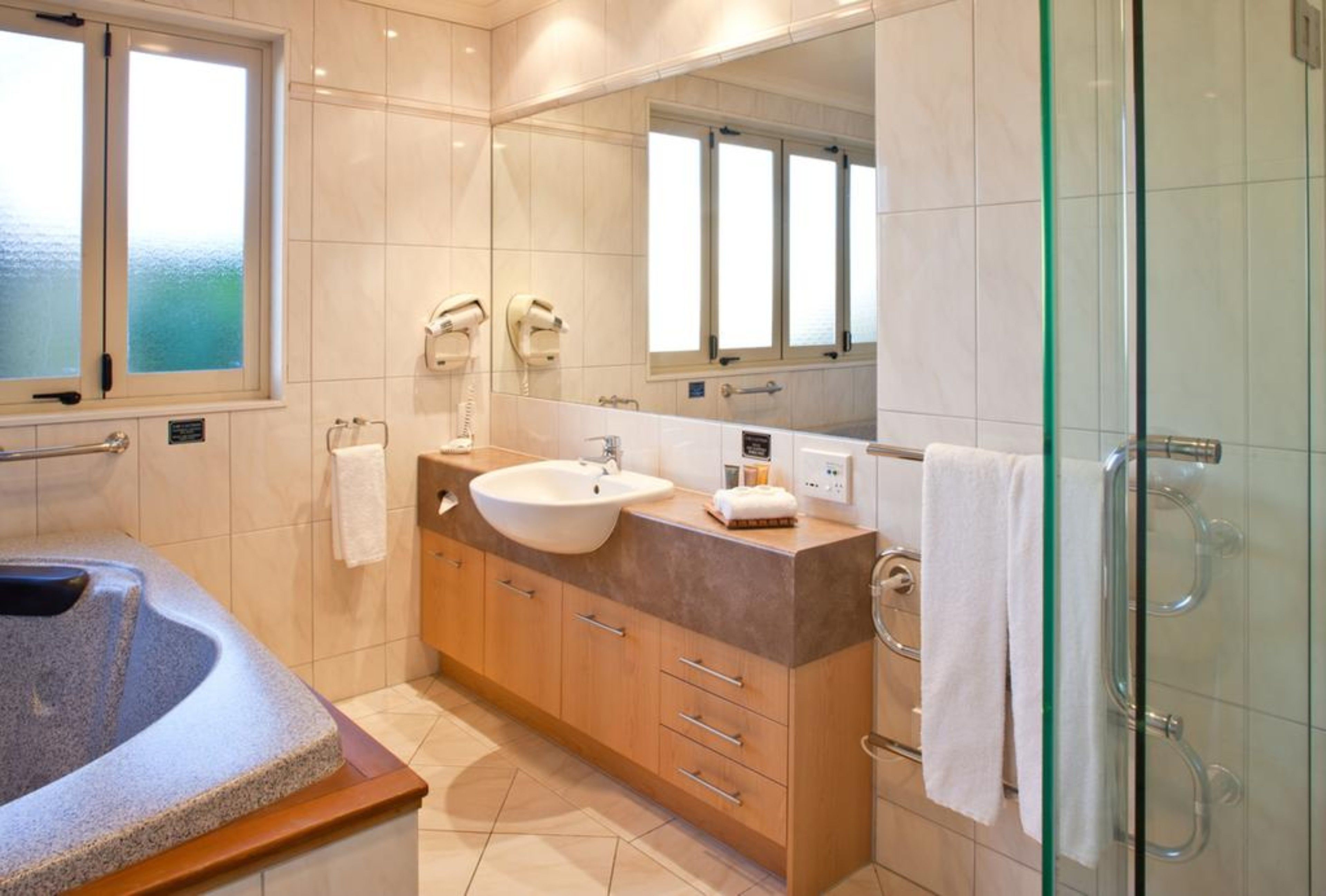 A modern bathroom with a large bathtub, a sink, and a glass shower enclosure.