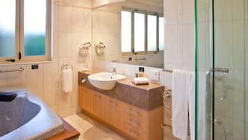 A modern bathroom with a large bathtub, a sink, and a glass shower enclosure.