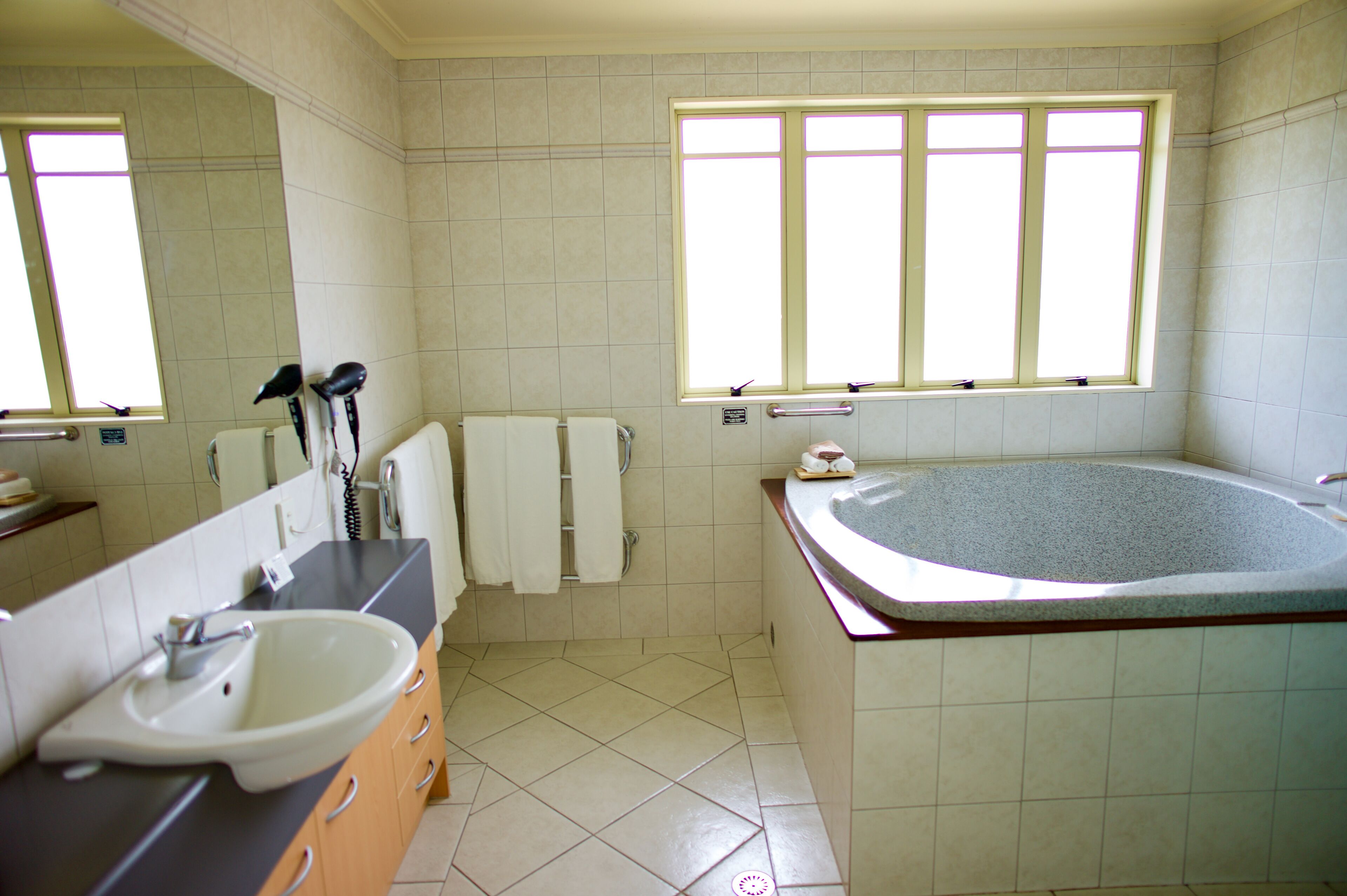 Un baño con una bañera grande, un lavabo y un espejo.