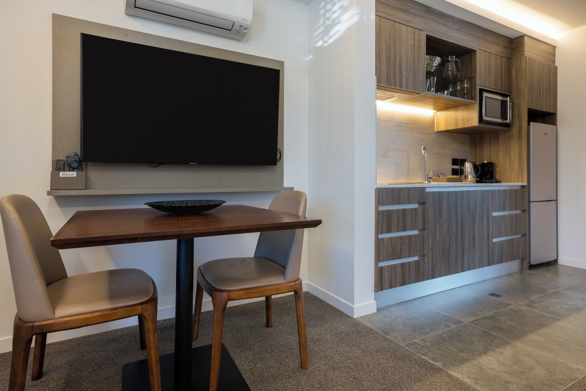 A modern kitchen with a flat-screen TV, wooden cabinets, and a built-in microwave.