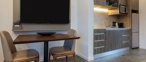 A modern kitchen with a flat-screen TV, wooden cabinets, and a built-in microwave.