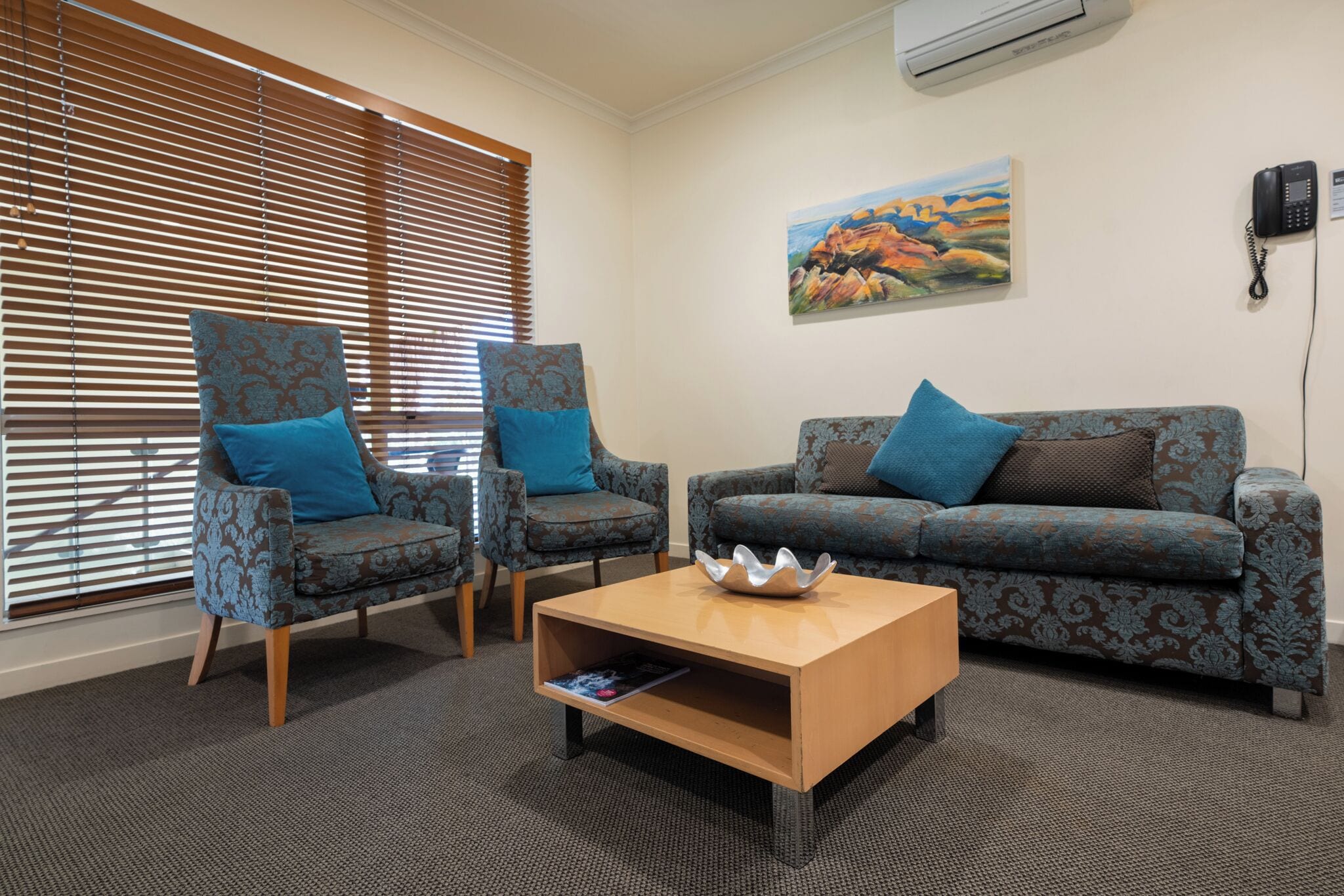 A room with two patterned armchairs, a sofa, and a wooden coffee table.