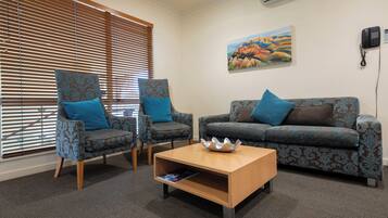 A room with two patterned armchairs, a sofa, and a wooden coffee table.