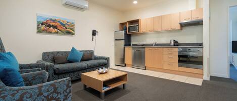 A compact living space with a sofa, coffee table, and a kitchenette area.