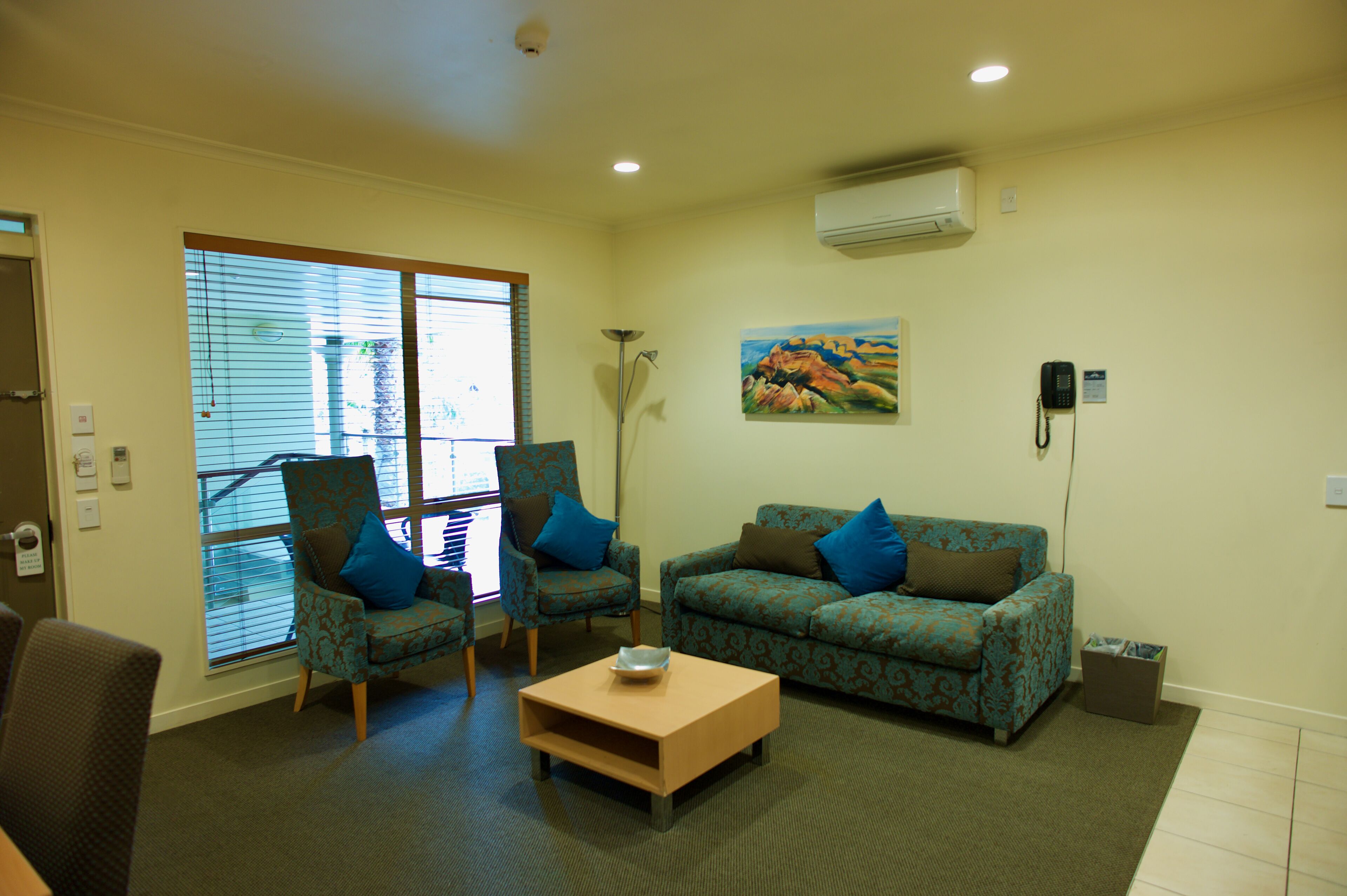 A living room with a sofa, two armchairs, a coffee table, and a painting on the wall.
