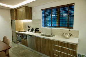 A modern kitchen with wooden cabinets, stainless steel appliances, a double sink, and a window with blinds.
