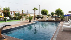 A rectangular swimming pool with a tiled deck, surrounded by lounge chairs and potted plants. - Felicioni (Pineto)
