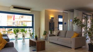 A modern living room with a grey sofa, a wooden coffee table, and several potted plants. - Felicioni (Pineto)