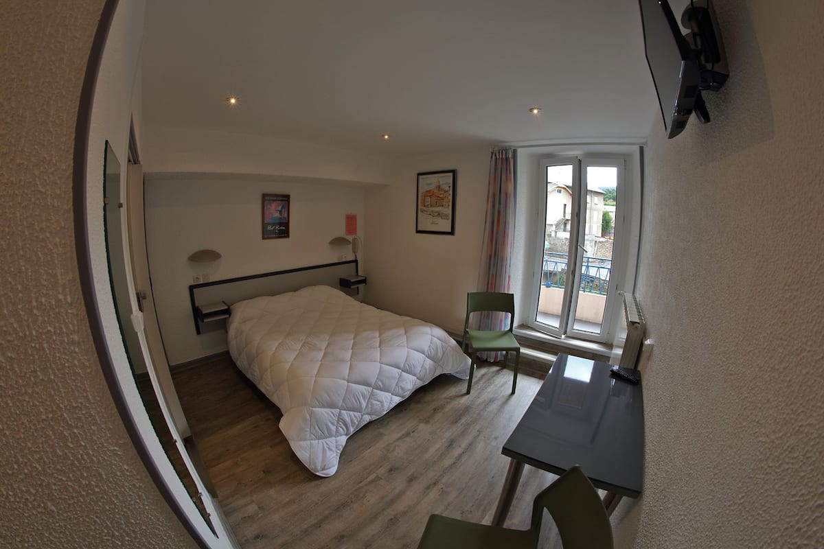 Une pièce comprenant un lit, un bureau, une chaise, une fenêtre et un tableau accroché au mur.
