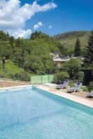 Piscina com espreguiçadeiras e vista para uma encosta verde.