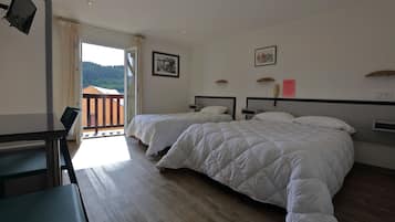 Une chambre d’hôtel avec deux lits, un bureau et un balcon donnant sur l’extérieur.