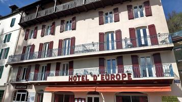 Un hotel llamado "HOTEL D'EUROPE" con una zona de recepción, asientos al aire libre y un letrero de restaurante.