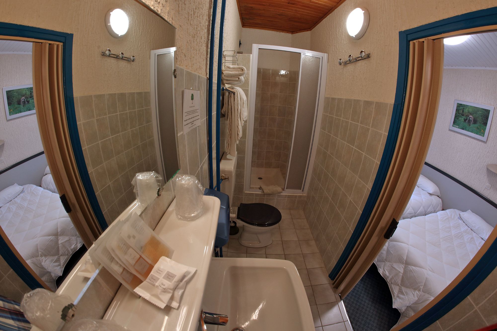 A bathroom with a shower, toilet, and sink. There are towels and toiletries on the sink.