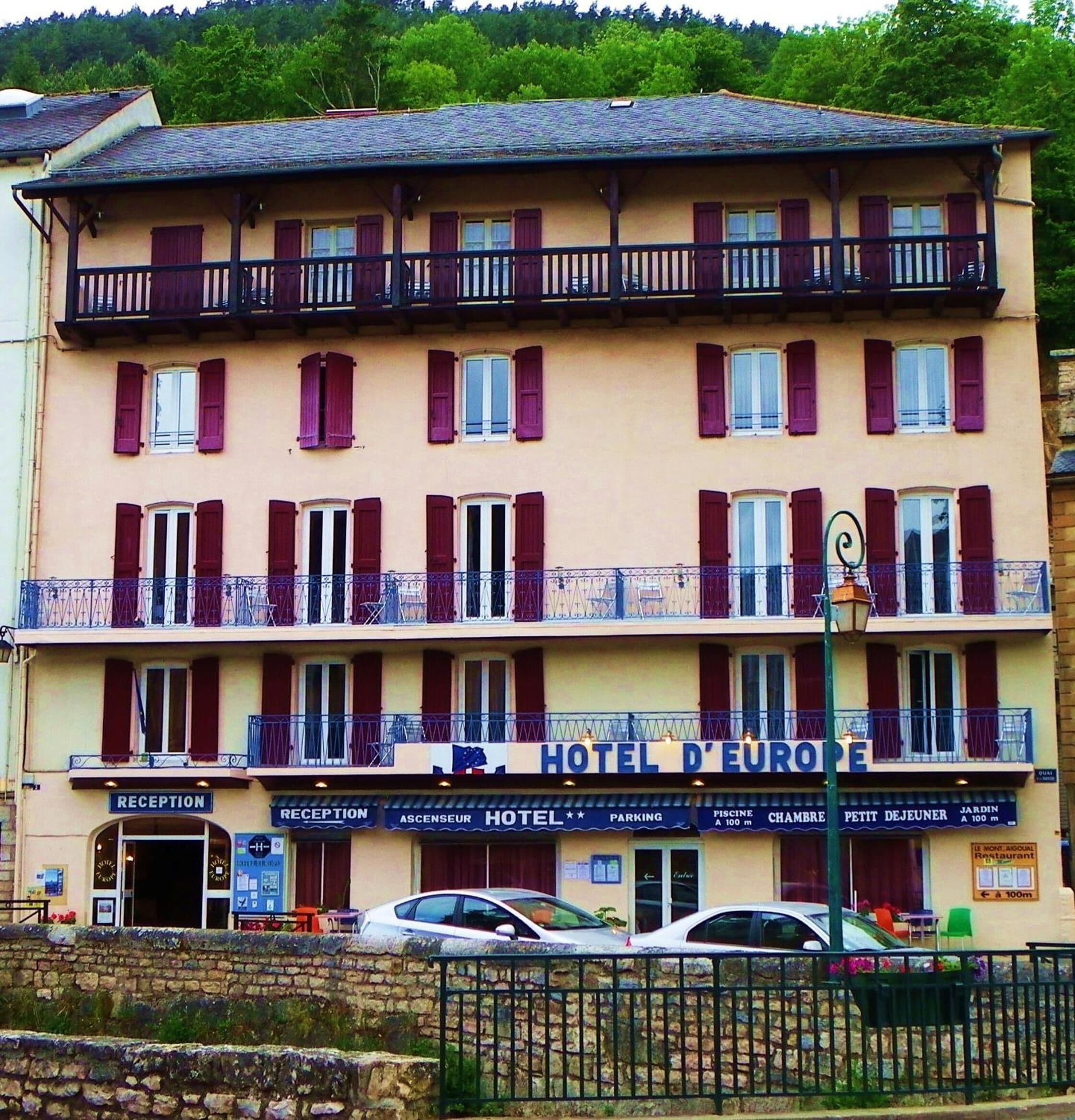 A multi-story hotel with balconies, a reception area, and signage for amenities like parking and a restaurant.