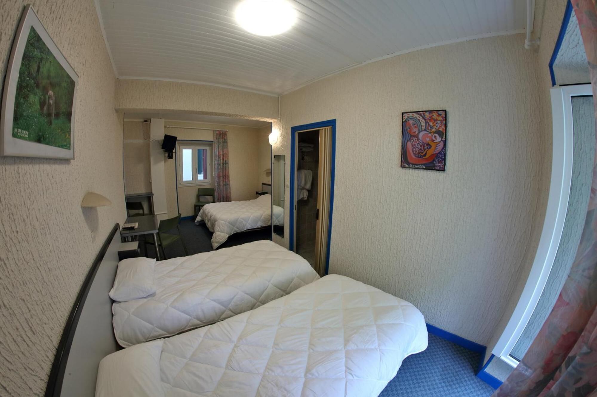 Hotelkamer met twee bedden, een bureau, een stoel, een spiegel, een schilderij en een raam.