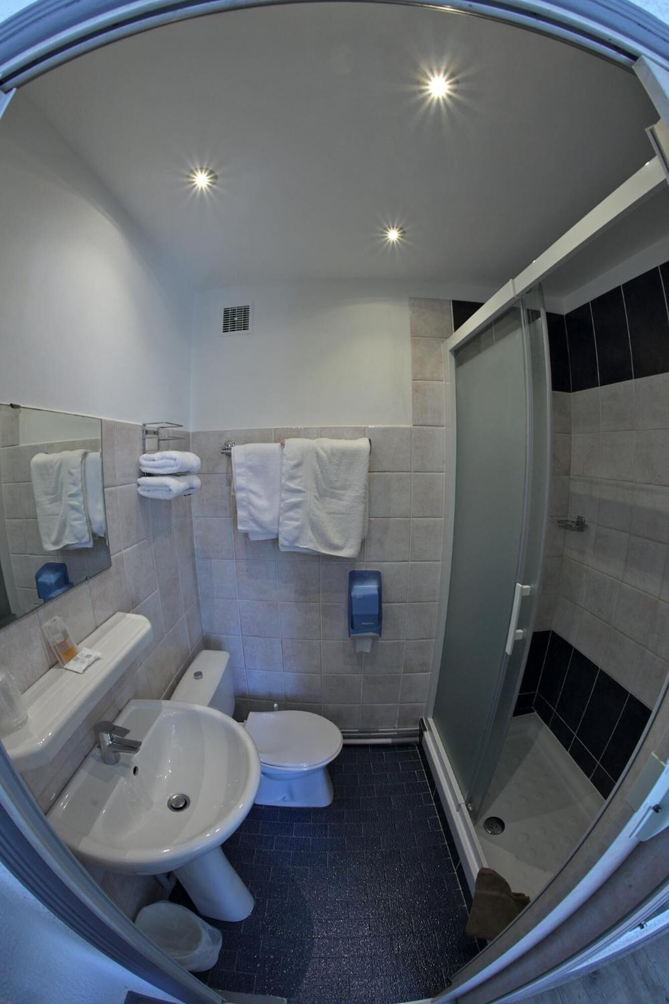 A compact bathroom with a sink, toilet, and shower.