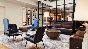 A modern lounge area with a glass partition, leather sofas, and a coffee table. - Hotel Pulitzer (Buenos Aires)