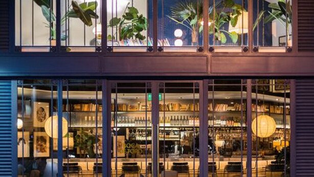 A bar with a variety of bottles and a seating area with tables and chairs. - Hotel Pulitzer (Buenos Aires)