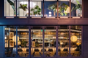 A bar with a variety of bottles and a seating area with tables and chairs. - Hotel Pulitzer (Buenos Aires)