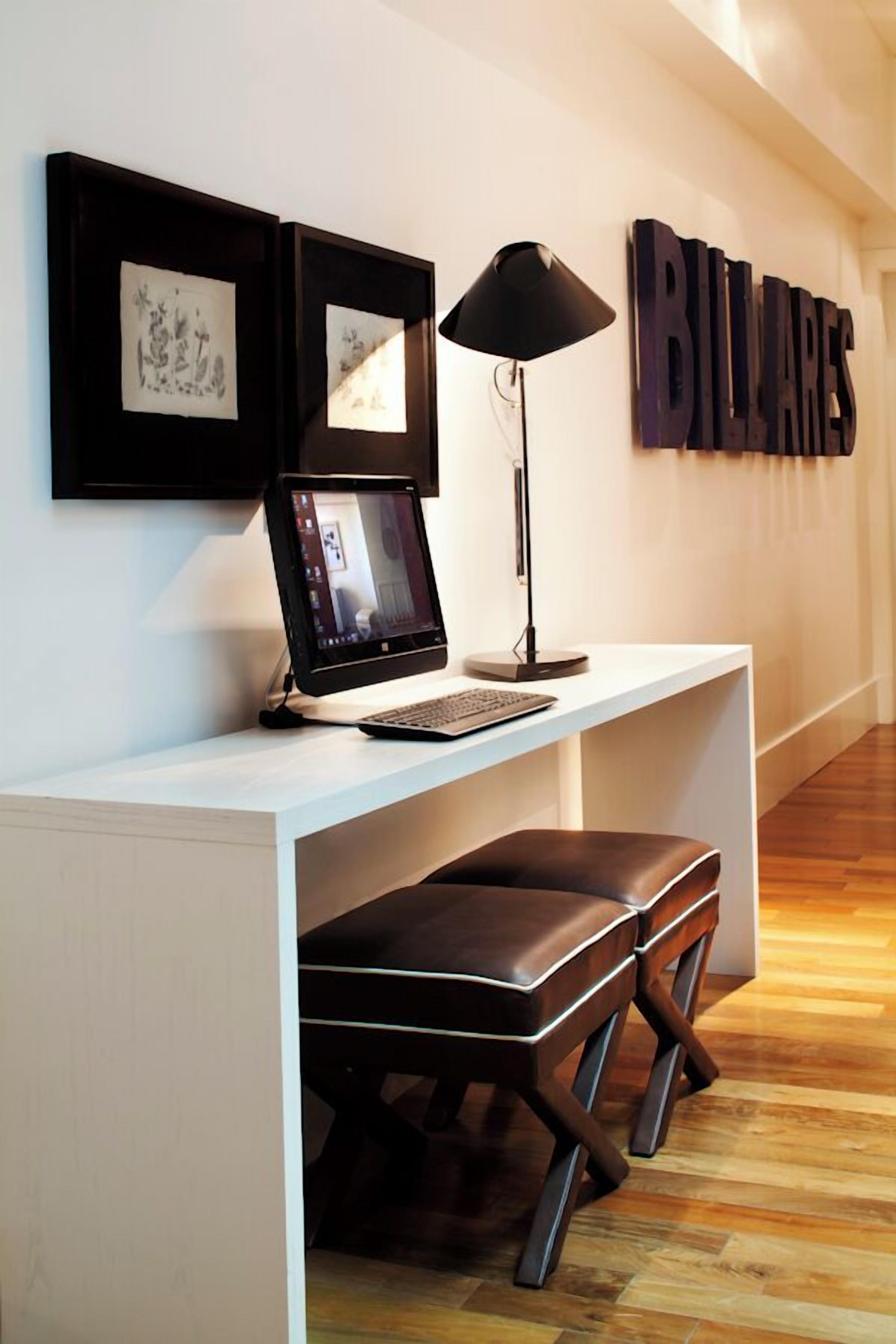 Een moderne kantoorruimte met een bureau, laptop en twee foto's in lijsten aan de muur.
