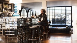 A modern bar area with high stools, a bar counter, and a large window offering a view of the city. - Hotel Pulitzer (Buenos Aires)