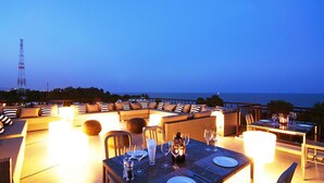 Ein Essbereich auf dem Dach mit Tisch für zwei Personen, mit Blick auf das Meer.