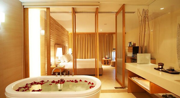 Una habitación de hotel moderna con una bañera grande, una zona de estar separada y un tocador con espejo.