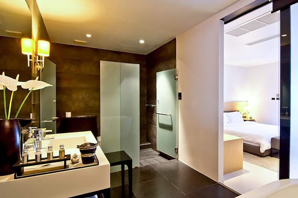 Une salle de bain moderne avec un grand miroir, un lavabo et un vase rempli de fleurs blanches.