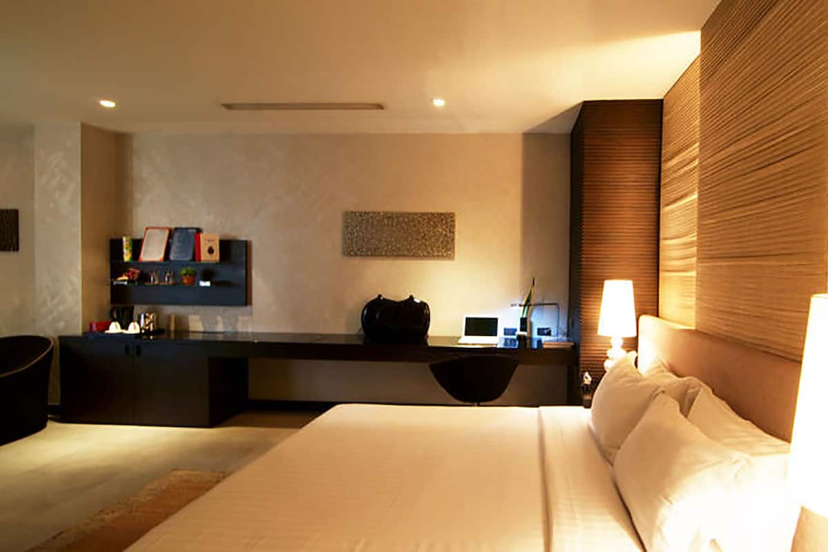 Une chambre d’hôtel avec un lit, un bureau, une chaise, une télévision et une lampe.