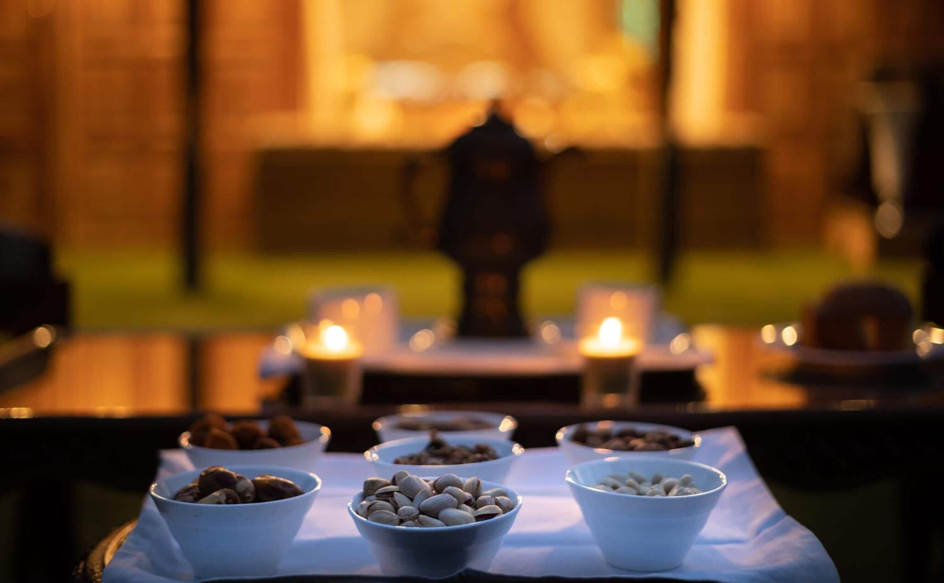 A table with bowls of nuts and candles in a dimly lit setting.