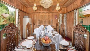 Un comedor con paneles de madera decorados, una araña y una mesa dispuesta para una comida.